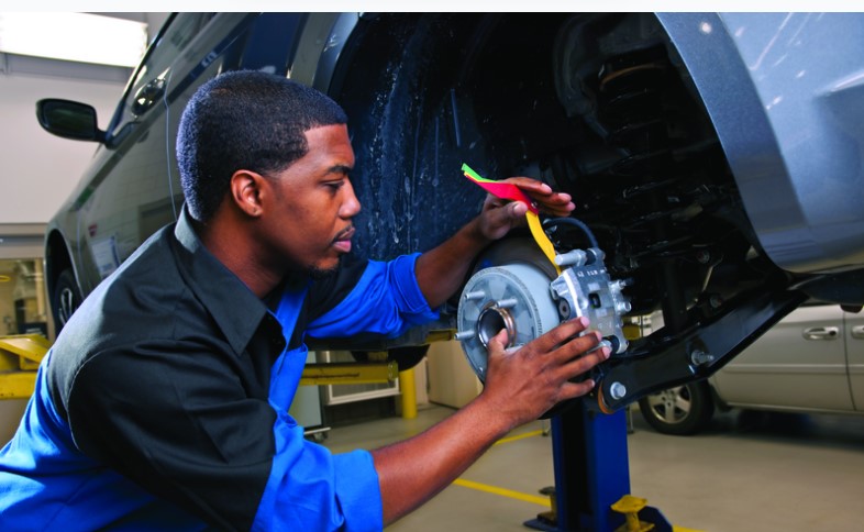 A mechanic working on the brake system of a vehicle in a professional auto service shop.