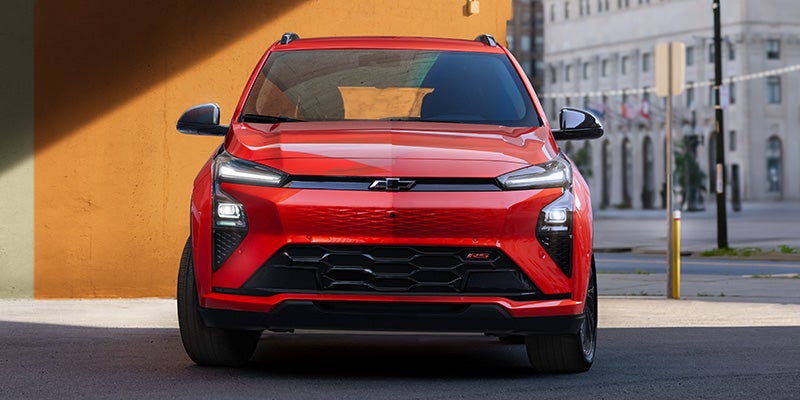 Front view of a red 2027 Chevrolet Bolt parked on a city street.